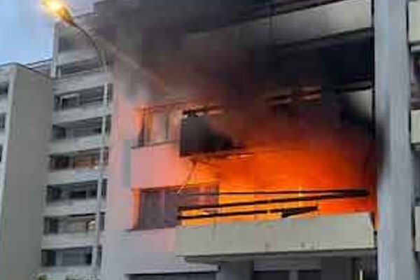 Ein weisses Gebäude, dass auf einem Balkon ein Feuer entfacht ist.